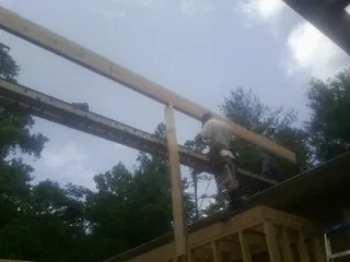 Carpenter setting a ridge beam over a new addition frame — Ice Dam Removal by Roofing Brothers in Grimes