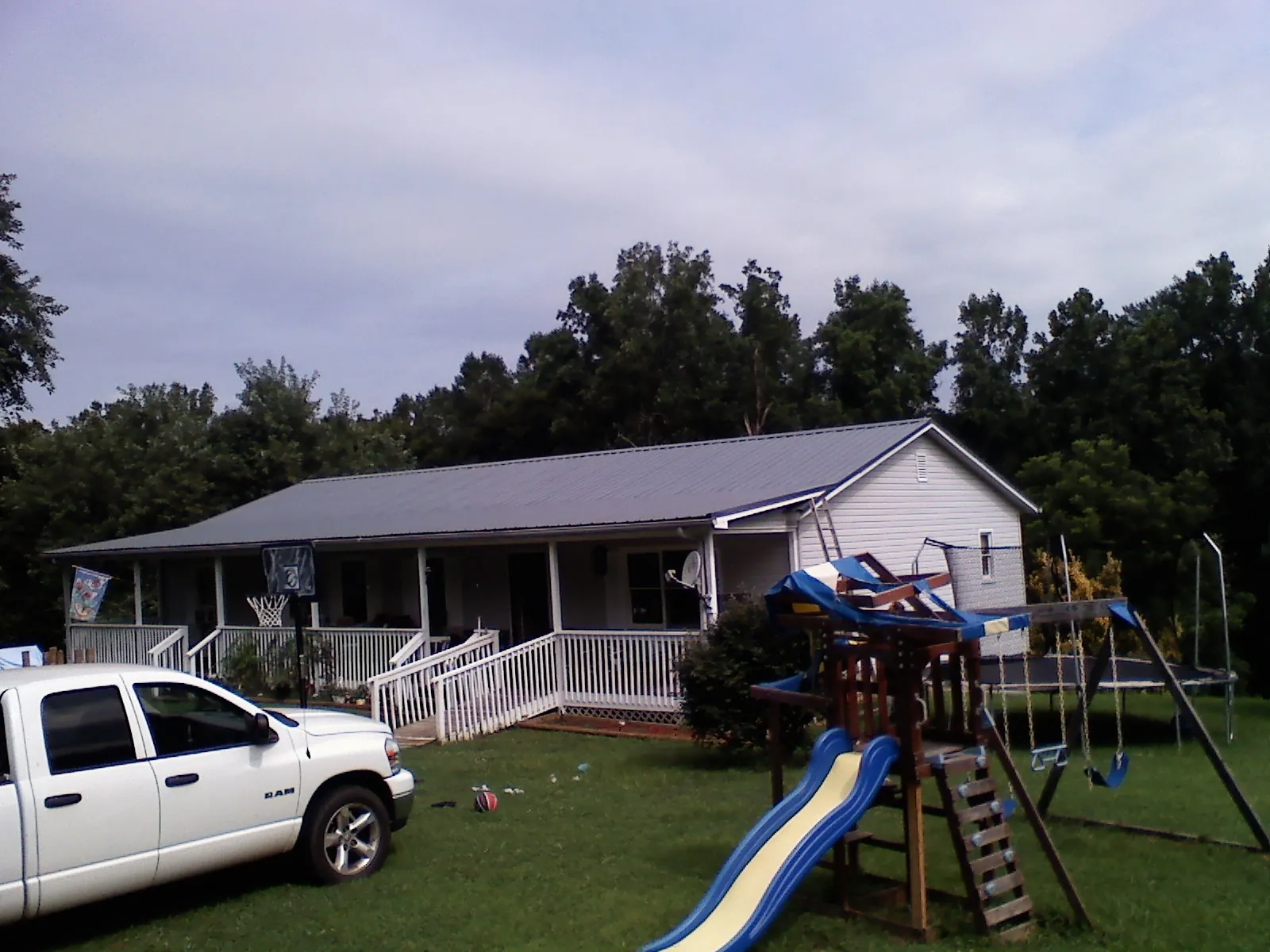 Dark metal roof on a country home with a full length front porch in Grimes
