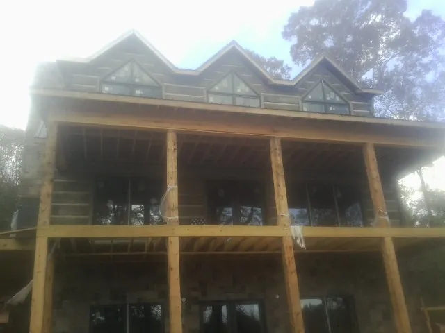Dormers and porch framing on a large log home under construction — Roof Coating work by our crew in Grimes