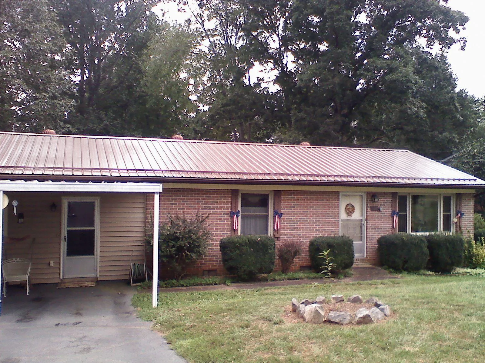Bronze metal roof and carport on a brick ranch home — Roof Repair work by our crew in Grimes