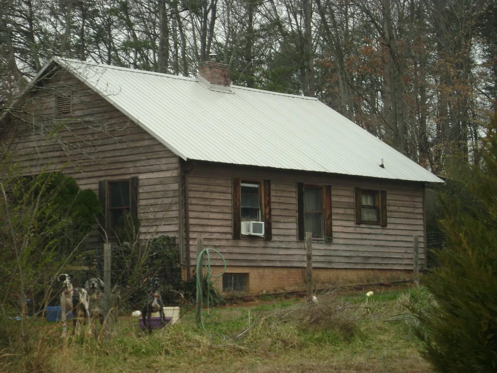 White metal roof on an old wood sided farmhouse, from a Metal Roof Installation job in Grimes