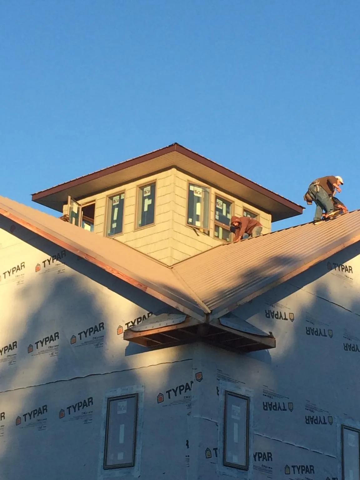 Roofers working around a rooftop cupola on a new metal roof at sunset — Roof Waterproofing in Grimes by Roofing Brothers